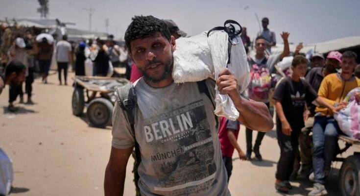 Omar al-Hobi, 43 éves, a Rafah-ból, egy zacskó ételt hordoz, amelyet a magánvállalkozó, a Gázai Humanitárius Alapítvány vezette egy disztribúciós központban, a déli Gázai övezetben, amikor június 10-én érkezett Khan Younis-i sátra.