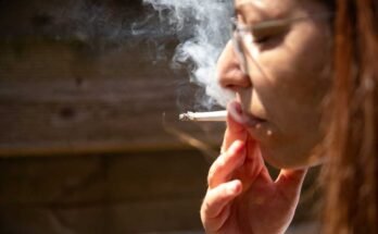 Egy nő május 30 -án cigarettát dohányzik a franciaországi Bretagne -i Kerlouanban. Az ország sok nyilvános helyen tiltja a dohányzást.