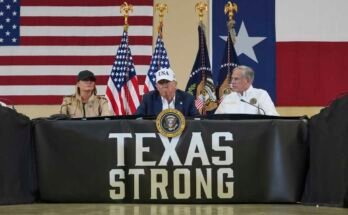 Donald Trump elnök beszél, míg a bal oldali Melania Trump első hölgy, és a texasi Greg Abbott kormányzója egy kerekasztal alatt hallgatja a texasi Kerrville első előadókkal és helyi tisztviselőivel a hónap elején.