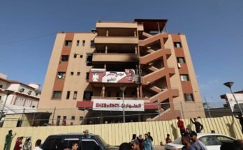 Az emberek és a forgalom átadja a Khan Yunis -i Nasser Kórház kerítését, amelyet hajnalban egy izraeli sztrájkban sújtottak, amely 2025. május 13 -án Gaza városát célozta meg.