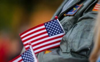 Robert Kielbowicz, aki 12 évét a Nas Oceana -i haditengerészetben töltötte, egy zászlót hajt végre a kabátjába, miközben tapsolt a Virginia Beach, Virginia, Virginia Day felvonulás során, 2024. november 11 -én.
