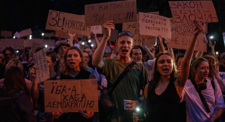 Az emberek énekelnek, miközben zászlókat tartanak a korrupcióellenes intézményeket célzó törvény elleni tüntetés során, kedden, Kyiv központjában.