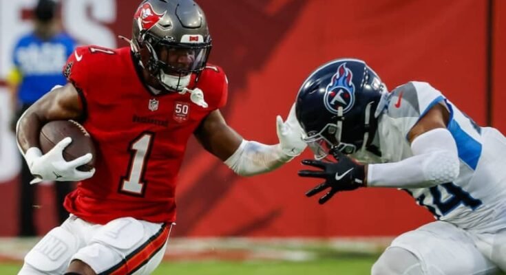 A Rachaad White-Arms Titans Safety Mike Brown, a szezon előtti mérkőzés első negyedévében, a szombati szezon előtti mérkőzés első negyedévében. © Jefferee Woo