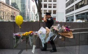 New York, New York - július 29.: A New York -i rendõrtiszt virágok előtt halad át a Midtown Iroda épület előtt, ahol egy fegyveres ember 2025. július 29 -én négy embert ölt meg New Yorkban. (Fotó: Stephanie Keith / Getty Images)