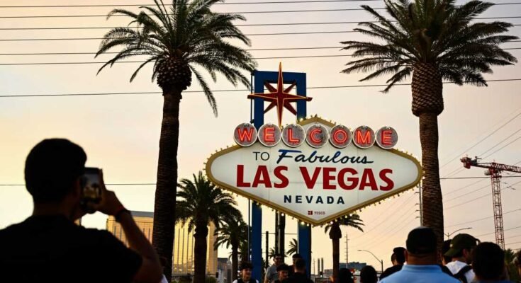 Az emberek fényképeket készítenek a mesés Las Vegas -i panel fogadásával egy ködös narancssárga ég alatt, míg a nap 2023. július 29 -én tart.