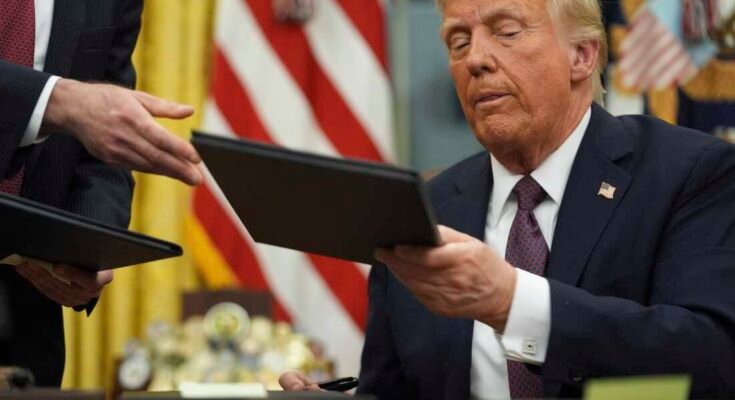 Donald Trump elnök január 20 -án aláírja a Fehér Ház Ovális Irodájában.