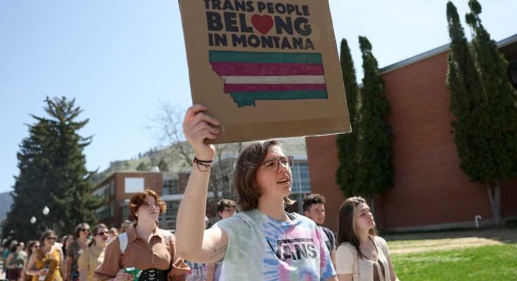 A transznemű jogok aktivistái jeleket tartanak, miközben átlépik a Montana Egyetem campusát 2023. május 03 -án, Missoula -ban, Mont.